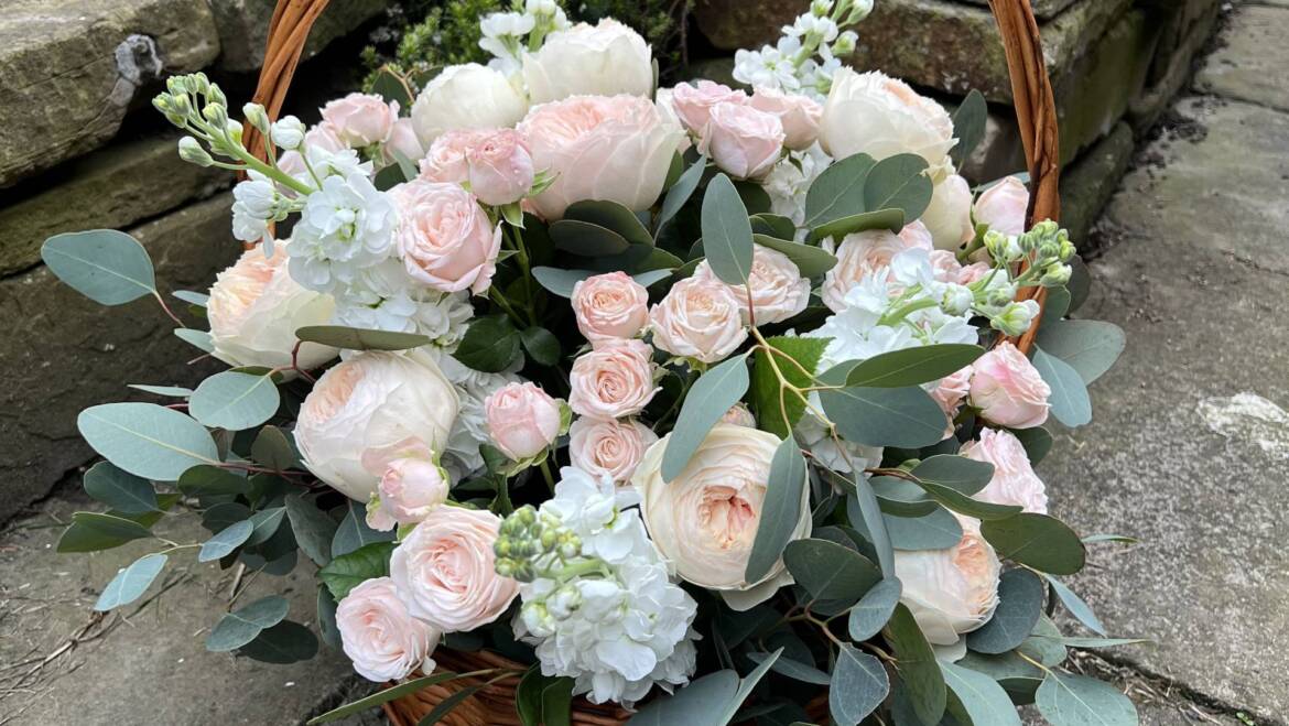 An elegant composition in a basket, featuring a harmonious blend of garden roses, delicate matthiolas, and lush eucalyptus.