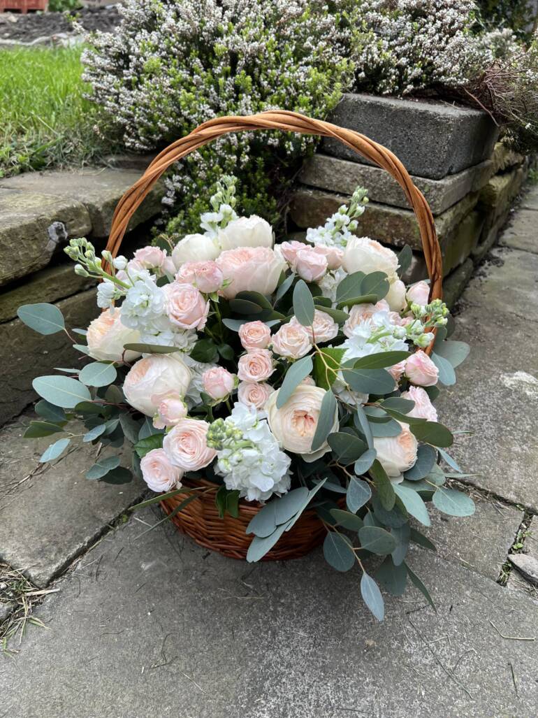 An elegant composition in a basket, featuring a harmonious blend of garden roses, delicate matthiolas, and lush eucalyptus.