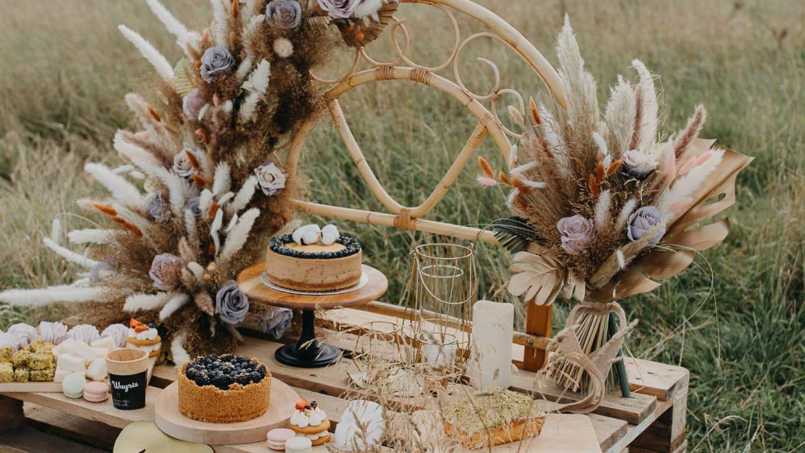 A spectacular candy bar designed for a brand photoshoot of a pastry shop, featuring a luxurious boho theme beautifully combined with artificial flowers. It resulted in a irresistible display that captivates the senses.