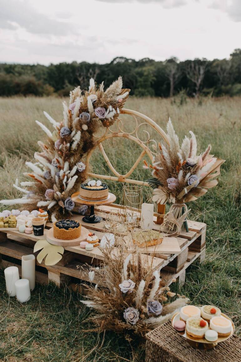 A spectacular candy bar designed for a brand photoshoot of a pastry shop, featuring a luxurious boho theme beautifully combined with artificial flowers. It resulted in a irresistible display that captivates the senses.