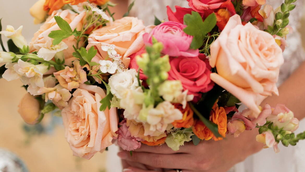 A vibrant bridal bouquet filled with bold summer blooms and fresh greenery, radiating energy, color, and a joyful, sun-kissed charm
