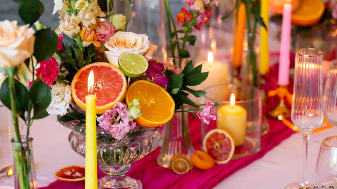 Bold, colourful  table flower arrangements, paired with fresh, juicy citrus fruits- a vibrant, lively, and refreshingly playful table setting.