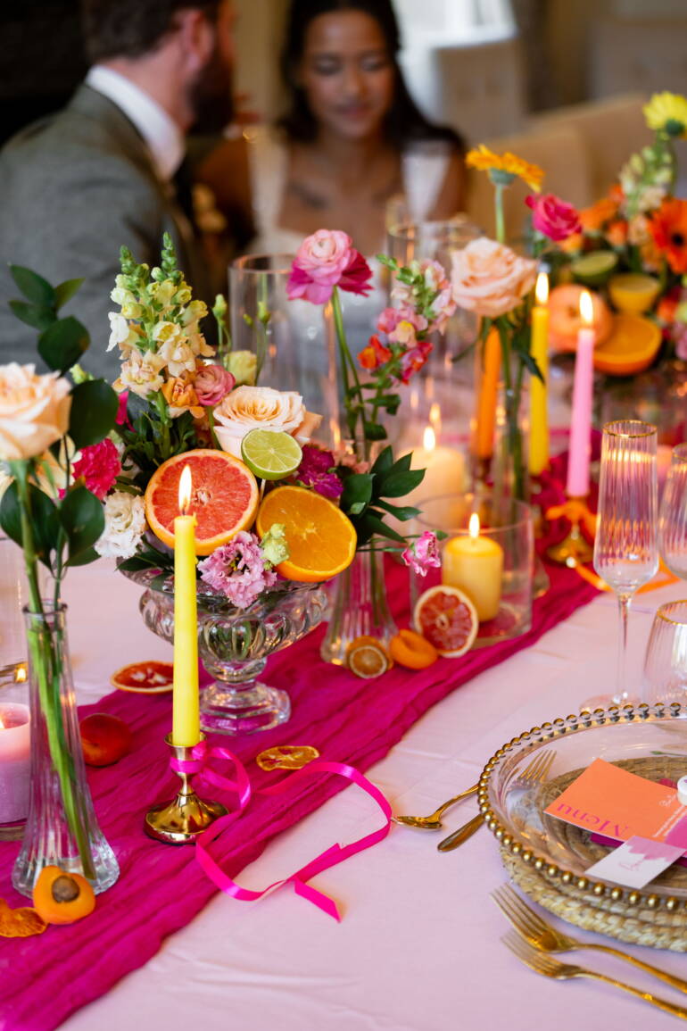 Bold, colourful  table flower arrangements, paired with fresh, juicy citrus fruits- a vibrant, lively, and refreshingly playful table setting.
