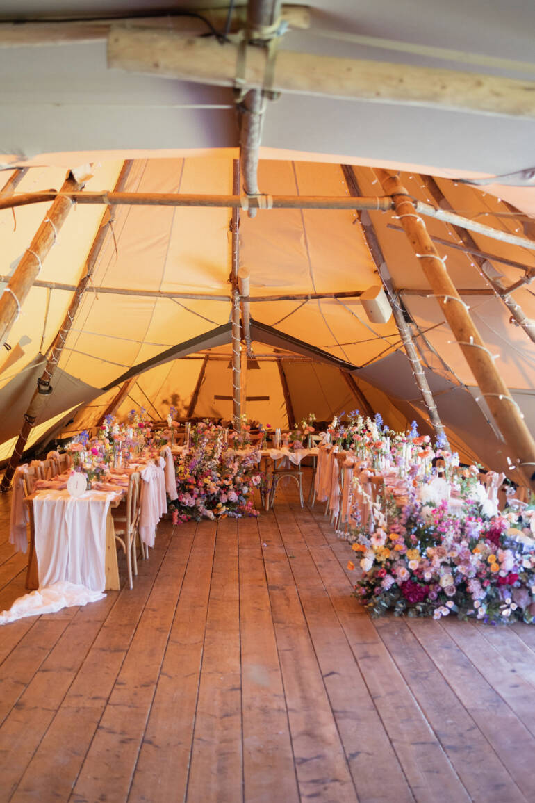 A pastel dream unfolding through the tipi, where flowers whisper like soft confetti and greenery drapes like a gentle, floating veil, turning the space into a cloud of romance and light