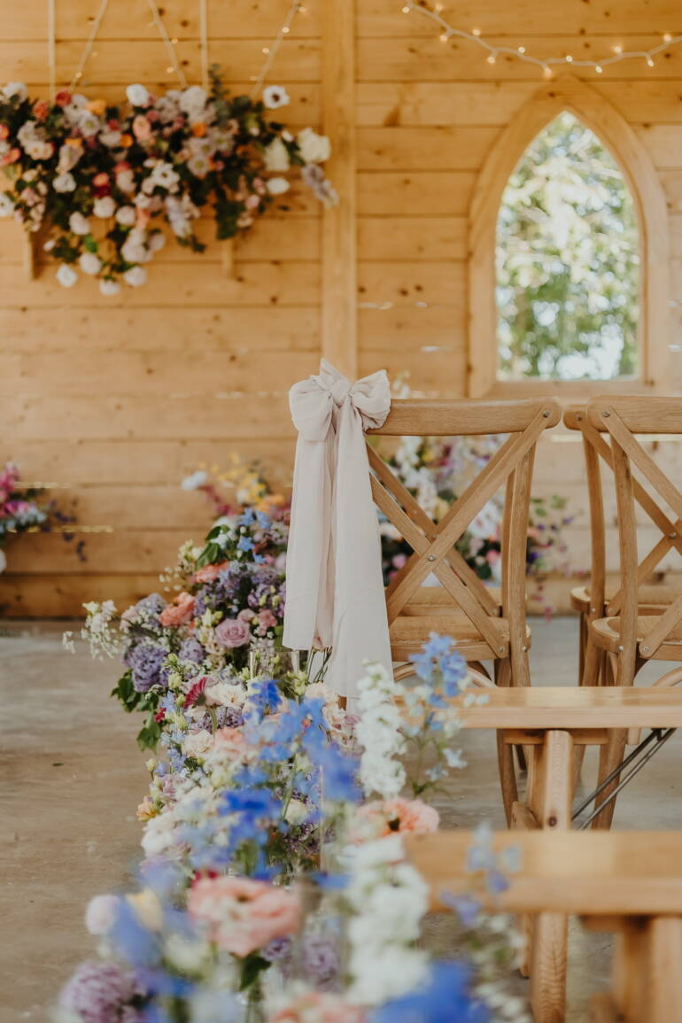 Ceremony space  filled with soft pastel blooms and gentle greenery, creating a serene, romantic, and airy floral setting